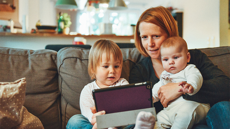 mother sitting on the couch with an infant and a toddler